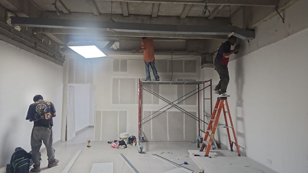 Equipo instalando paredes de tablayeso con andamio