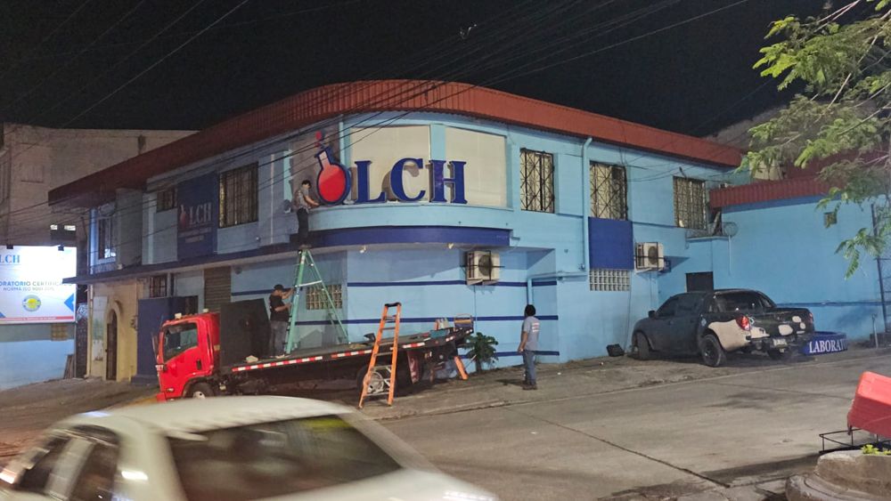 Equipo instalando las letras LCH en la fachada de noche