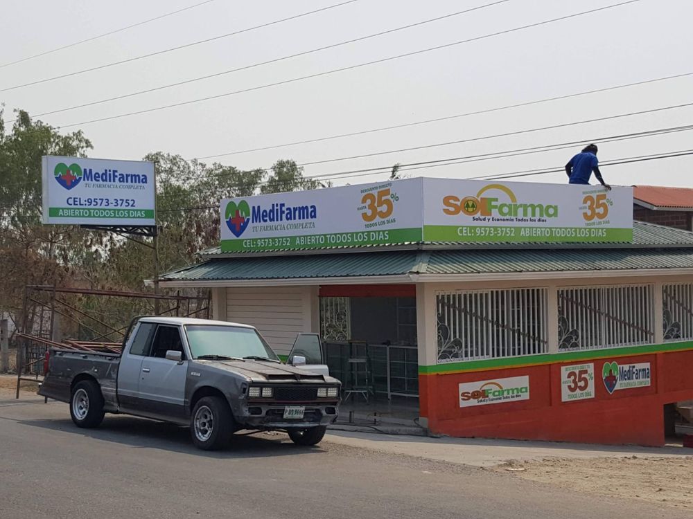 Técnico instalando el rótulo sobre el techo de la farmacia